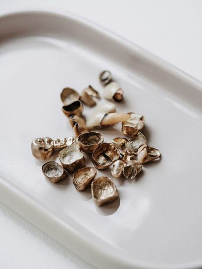 Ausgebautes Zahngold mit Goldkronen auf einer weißen Schale