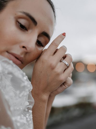 Braut lehnt den Kopf an ihre Hand und schließt die Augen, am Ringfinger der Trauring mit Brillantreihe